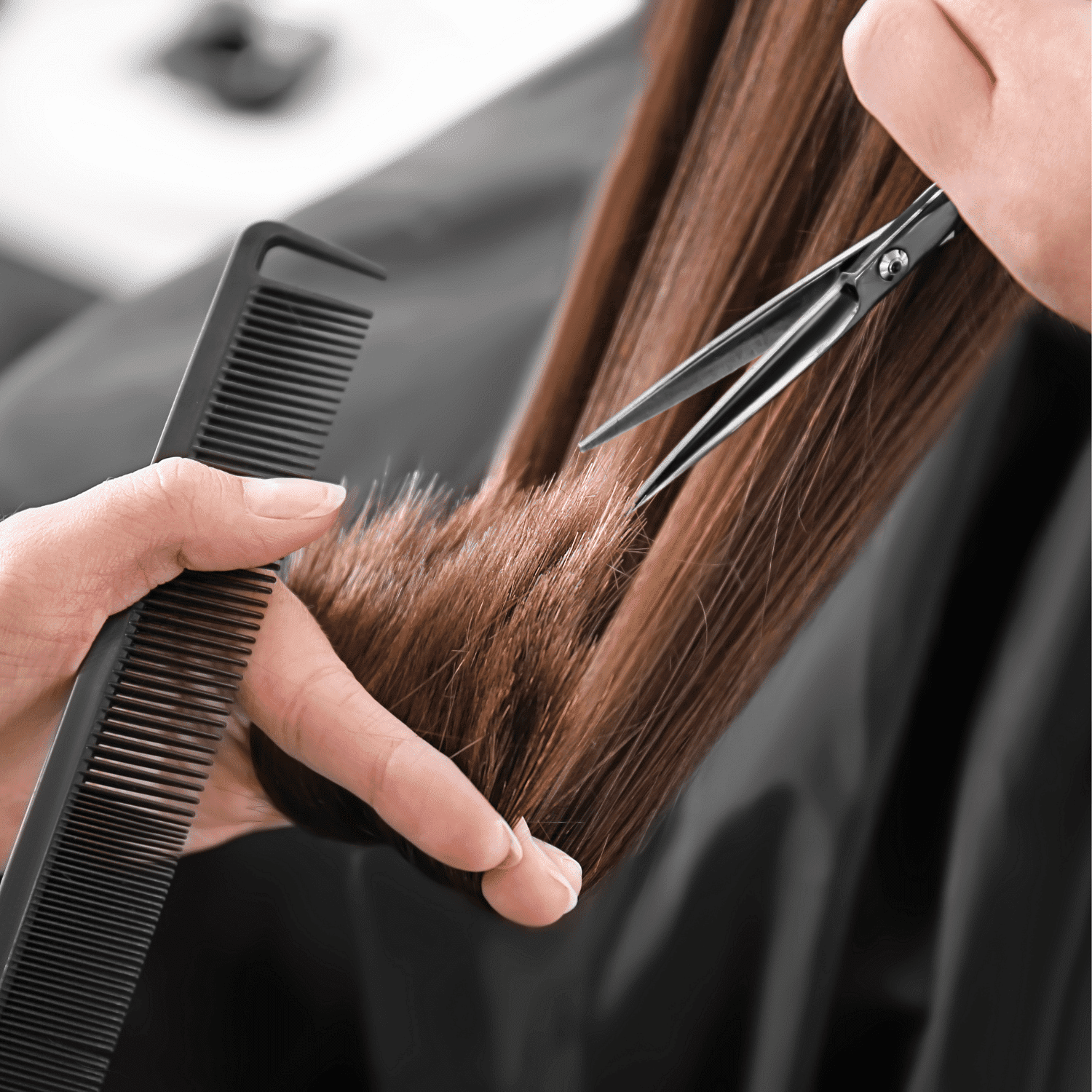 Hairstylist using scissors and comb to trim long brown hair.
