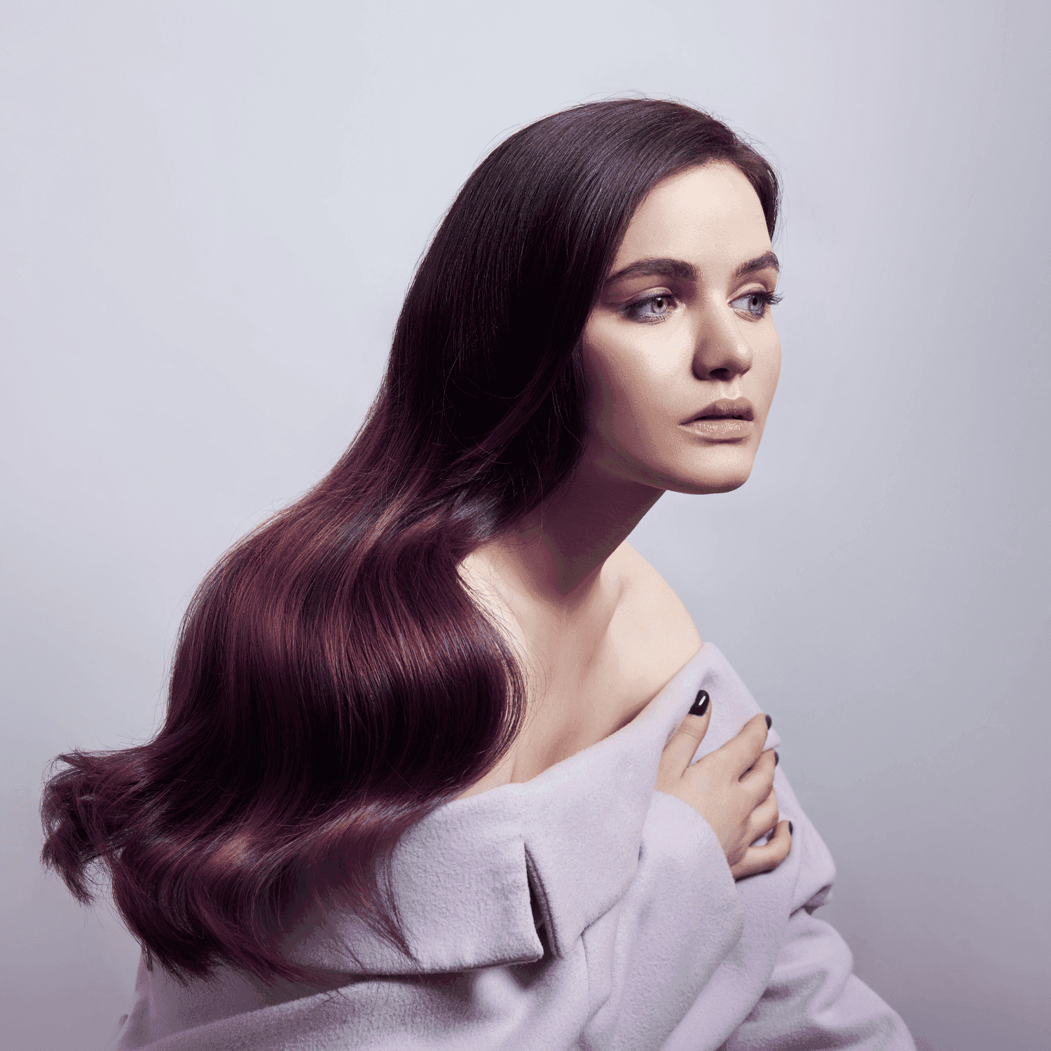 Woman with long, flowing purple-tinted hair in an off-shoulder lavender top, gazing thoughtfully.